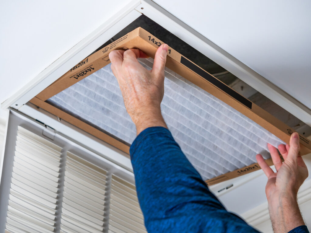 HVAC technician replacing a home air filter in North Highlands