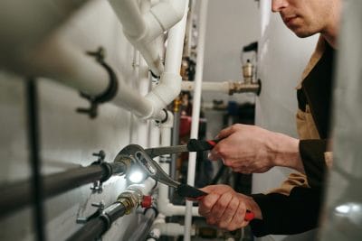 Technician inspecting commercial plumbing pipes in North Highlands