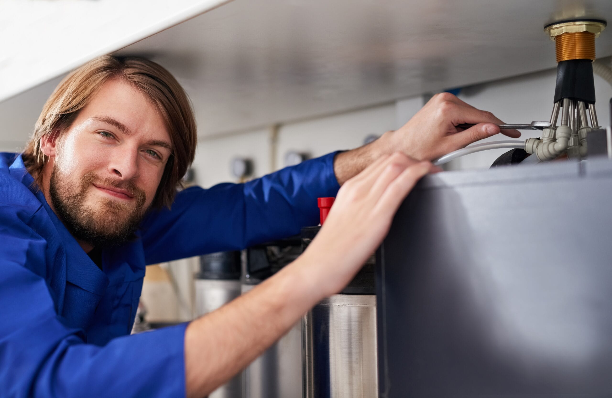 Technician servicing a residential water heater tank in North Highlands